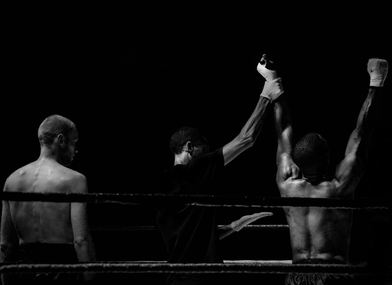 Black and white image capturing a victorious boxing moment in the ring.