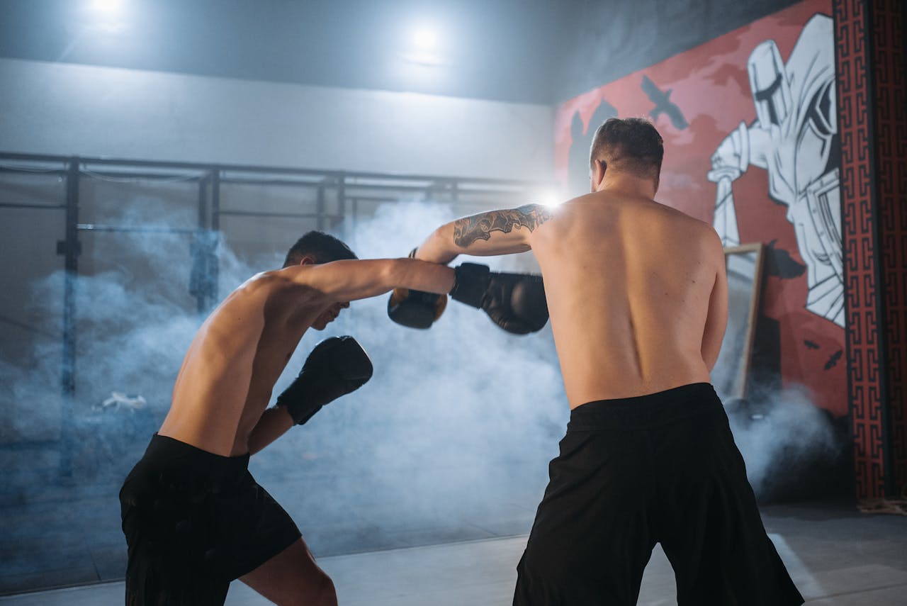 Crafting Captivating Headlines: Your awesome post title goes here Two shirtless men sparring in a smoky gym setting, showcasing powerful boxing techniques.